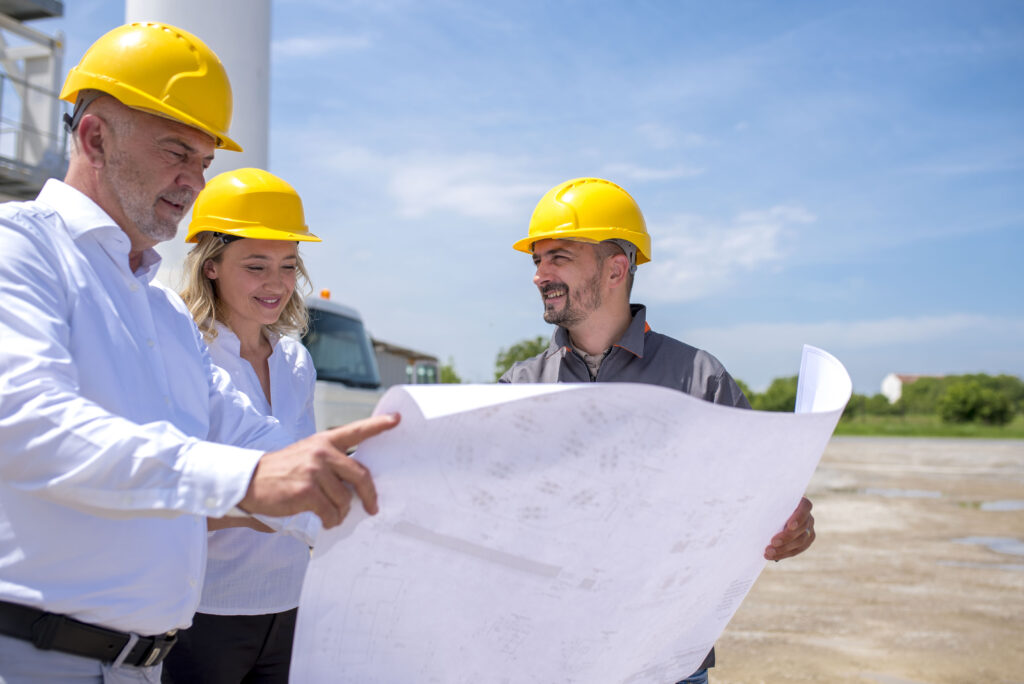 group of construction workers looking at the plans and documents under the sunlight